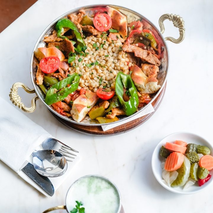 Plato de pollo con verduras, tomate, frijoles y guarnición de encurtidos.