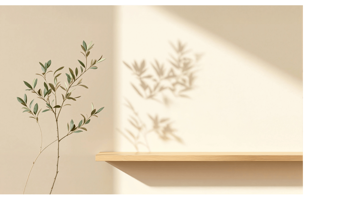 Rama de planta con sombras proyectadas sobre una pared clara y estante de madera.